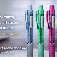 Tre penne a sfera Faber-Castell Poly Ball View dai colori azzurro, verde e fucsia con fusto trasparente e impugnatura ergonomica, fotografate su una scrivania con sfondo sfocato, ideali per una scrittura fluida e confortevole anche dopo ore.
