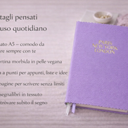 Taccuino lilla elegante con copertina in pelle vegana, presentato con testo overlay che evidenzia formato A5, carta a punti, 240 pagine e doppio segnalibro per l’uso quotidiano.

